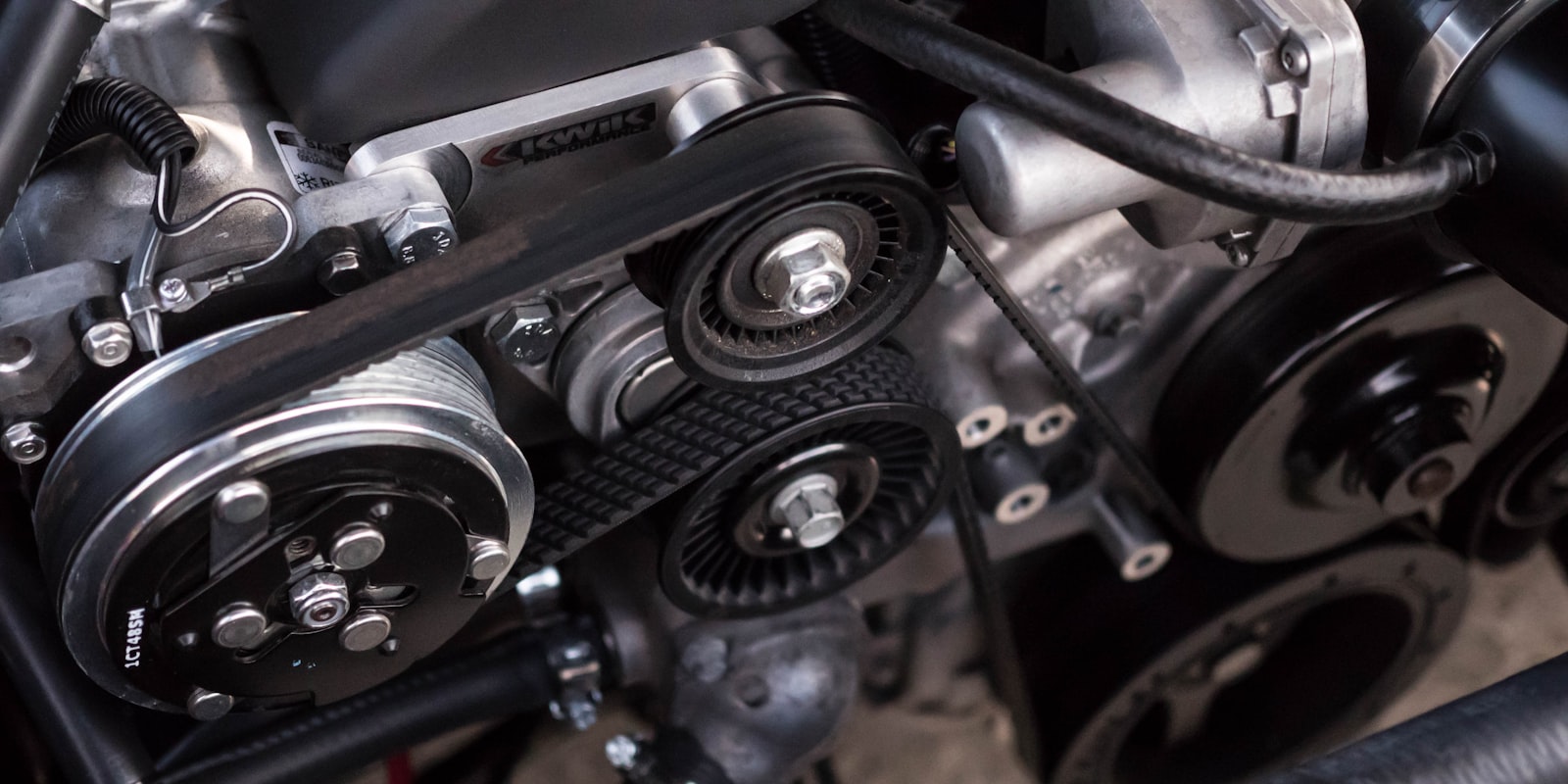 Nærbilde av en motor med remmer, trinser og blanke metalldeler